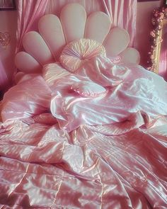 an unmade bed with pink sheets and pillows