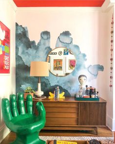 a living room with green chairs and a large painting on the wall behind an arm chair