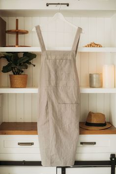 an apron hanging on the wall next to some shelves with candles and other items in it