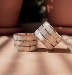 two wedding bands sitting next to each other on top of a wooden table with potted plants in the background