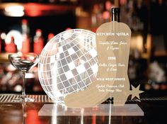 a wine glass sitting on top of a table next to a plaque with an image of a disco ball