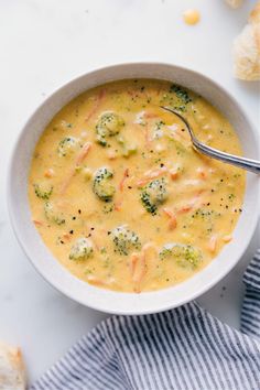 a white bowl filled with broccoli and cheese soup on top of a table