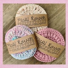 three crochet scrubs with labels on them sitting on a wooden surface together