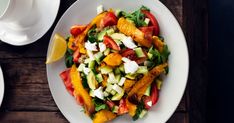 a white plate topped with lots of veggies on top of a wooden table