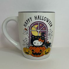 a white coffee mug with a hello kitty on it's side and the words happy halloween