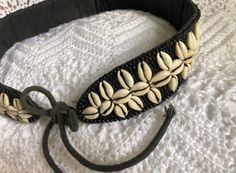 a close up of a headband on a white bed with black string and beads