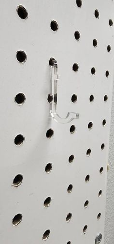 a white pegboard with holes on it and a hook in the middle that is attached to the wall