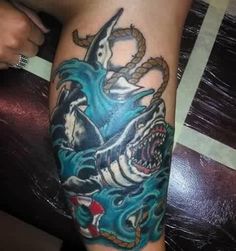 a man with a tattoo on his arm that has a shark in the middle of it