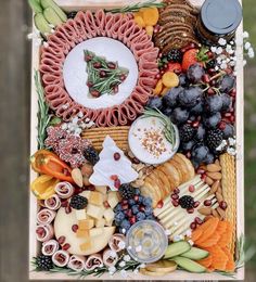 an assortment of cheeses, crackers, and fruit arranged in a wooden box