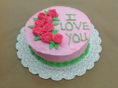 a pink cake decorated with roses and the words i love you