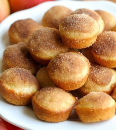 a white plate topped with sugared donuts on top of a red and white checkered table cloth