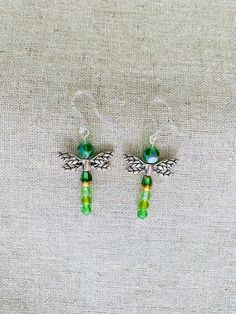 Approximately 2 inches in length, including the plastic earring hooks. The earrings display different shades of greens and yellows. Green Metal Clip-on Earrings For Gift, Green Metal Drop Clip-on Earrings, Handmade Green Crystal Metal Earrings, Nickel Free Green Metal Earrings, Green Metal Earrings For Gift, Nickel-free Green Metal Earrings, Green Crystal Earrings For Jewelry Making, Hypoallergenic Metal Beaded Drop Earrings, Adjustable Drop Earrings With Hypoallergenic Hooks