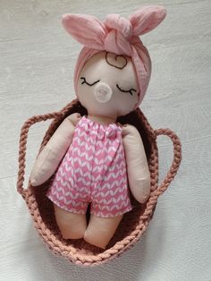 a teddy bear in a basket with a pink hairdow on it's head