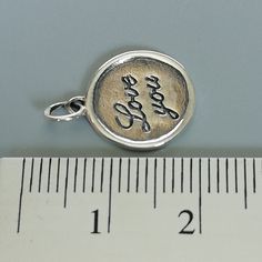 ▪︎ ONE sterling silver round charm with LOVE YOU inscribed on it. ▪︎ Size: 13 x 15 mm ( 17mm with hoop) Weight: 1.3 gm ▪︎ This is a multi functional charm and can be used with neck chains, ear hoops, bracelets, anklets, key chains etc. ▪︎ This pendant is handmade with hypoallergenic sterling silver, and is nickel free. Comes with a 925 mark for authenticity. ▪︎ Please note: Price listed is for ONE charm. This pendant comes WITHOUT the chain, however, you can add a snake neck chain, bracelet chai Silver Round Pendant Charms For Everyday, Personalized Minimalist Sterling Silver Charms, Minimalist Personalized Sterling Silver Charms, Minimalist Round Charms For Gifts, Minimalist Round Gift Charms, Engraved Sterling Silver Round Pendant Charms, Personalized Small Charms For Gifts, Handmade Round Charms For Gifts, Handmade Charms As Gifts