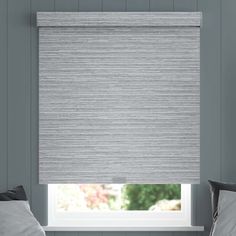 a bedroom with grey walls and a window covered in roman blind shades that match the bedding