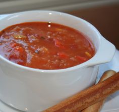 a white bowl filled with soup next to some breadsticks on top of a plate