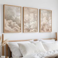 three paintings hanging on the wall above a bed with white linens and pillows in front of them