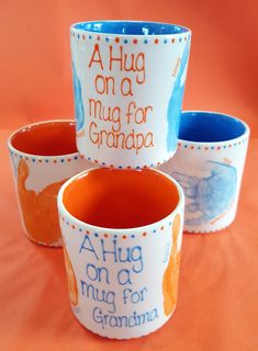 three ceramic cups with words on them sitting next to each other in front of an orange background