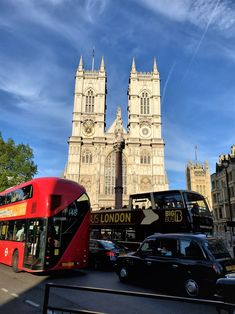 a red double decker bus driving down a street next to a tall building with two towers