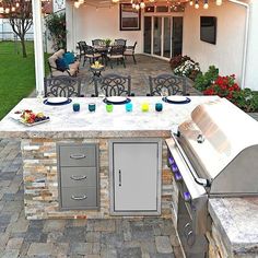 an outdoor kitchen with grill, sink and table set up for dinner on the patio