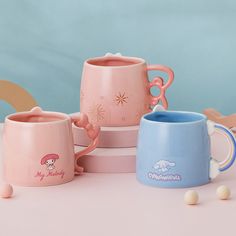 three pink and blue coffee mugs sitting next to each other on top of a table