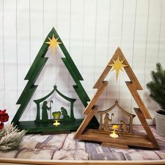 three wooden christmas trees with nativity scene on top and candles in the bottom one