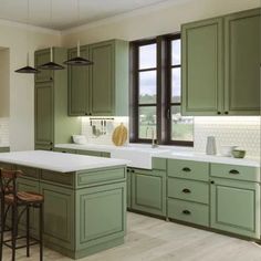 a large kitchen with green cabinets and white counter tops, along with an island in the middle