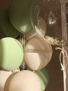 some balloons are hanging from the ceiling with white and green ribbons on them in front of a mirror