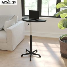 a laptop computer sitting on top of a table next to a white couch in a living room