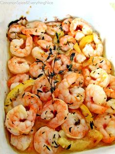 a casserole dish with shrimp, lemon and herbs on top is ready to be eaten