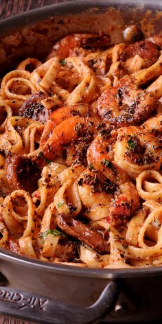 pasta with shrimp and tomato sauce in a pan on a wooden table top, ready to be eaten