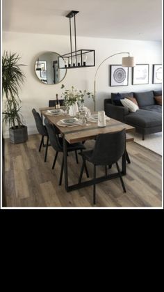 a dining room table and chairs in front of a couch with mirrors on the wall