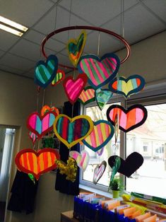 colorful paper hearts hanging from the ceiling in front of a window