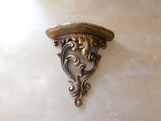 a wall mounted clock on the side of a white wall with an ornately carved design