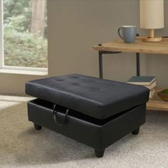 a black ottoman sitting on top of a carpeted floor next to a coffee table