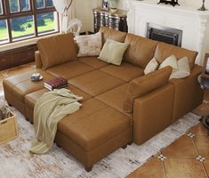 a living room with a large brown leather couch and pillows on the floor next to a fire place