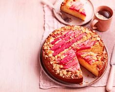 a cake sitting on top of a wooden table next to a cup and saucer