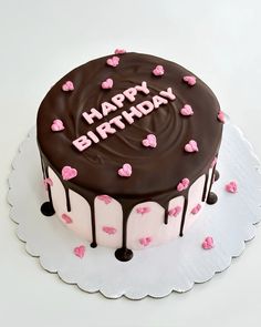 a birthday cake with chocolate frosting and pink hearts