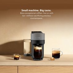 a coffee maker sitting on top of a wooden counter next to two cups of coffee