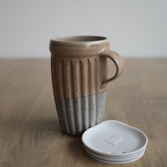 a coffee cup sitting on top of a wooden table next to a white saucer