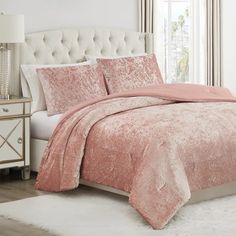 a bed with a pink comforter and pillows