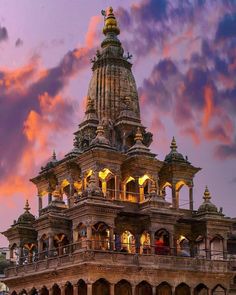 an ornate building lit up at night with clouds in the background