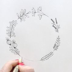 someone is drawing a floral wreath on paper