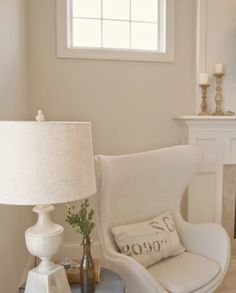 a white chair sitting next to a fireplace in a living room with a lamp on top of it