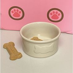 a dog bowl with a bone in front of it and a pink box behind it