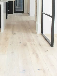 an empty kitchen with white walls and wood floors is seen in this image from the hallway