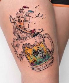 a woman's thigh with a beer mug and pirate ship tattoo on the side