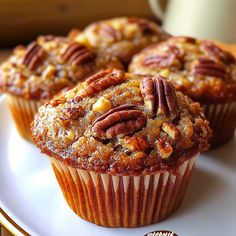 three muffins on a white plate with pecans