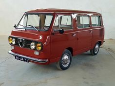 an old red van is parked in a room with white walls and concrete flooring