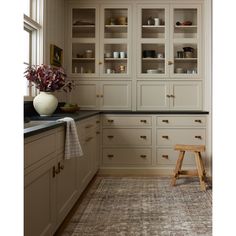 a large kitchen with white cabinets and black counter tops, an area rug on the floor